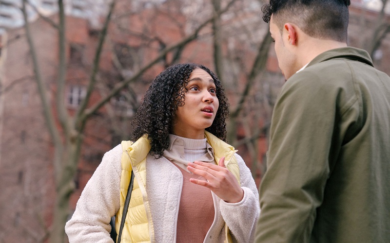 Young woman standing in front of a young man looking fearful