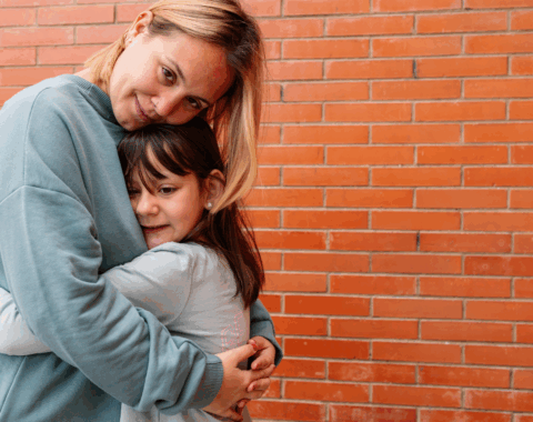 mother and young daughter hugging looking at camera